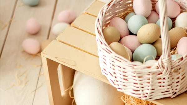 Wooden crate with Easter basket on top filled with colorful easter eggs